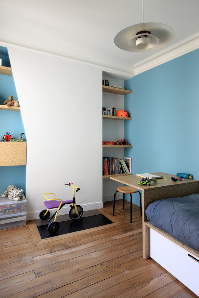 Idée de décoration pour une chambre de garçon de 4 à 10 ans design de taille moyenne avec un bureau, un mur bleu et un sol en bois brun.