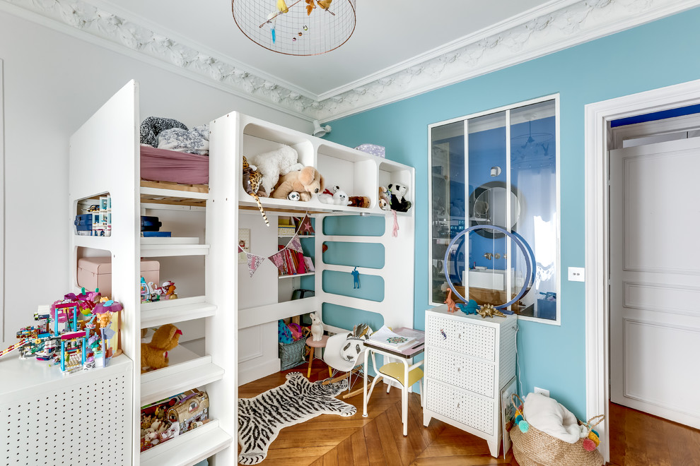 Modelo de dormitorio infantil de 4 a 10 años ecléctico con paredes azules y suelo de madera en tonos medios