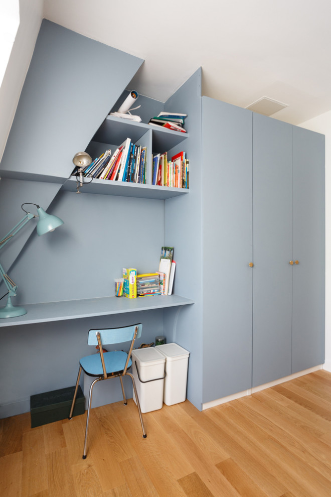 Cette photo montre une chambre d'enfant de 4 à 10 ans tendance de taille moyenne avec un mur bleu, un sol beige et un sol en bois brun.