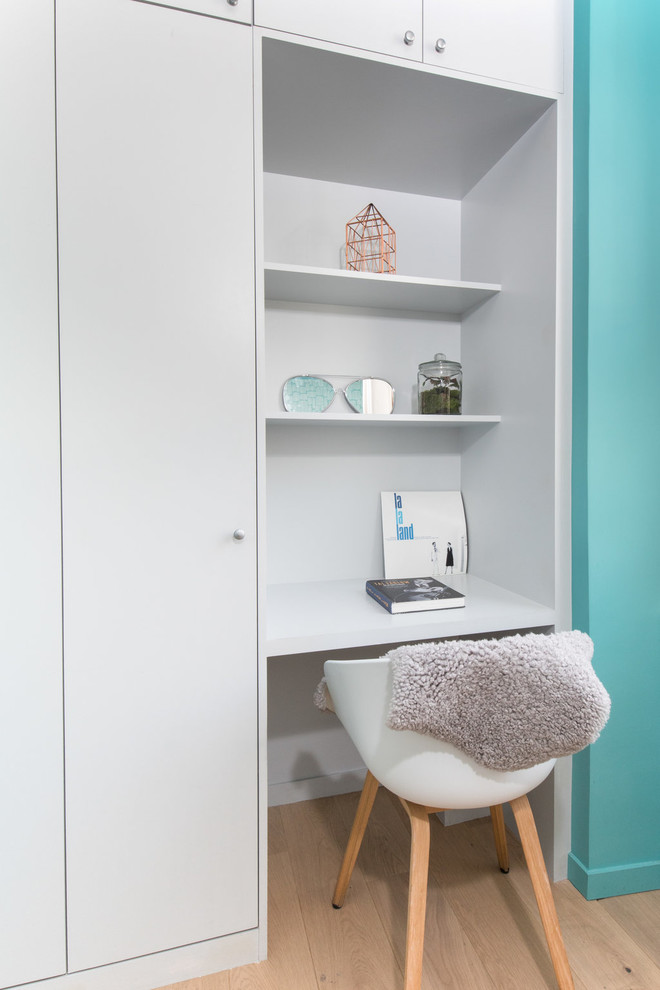 Cette image montre une petite chambre d'enfant design avec un bureau, un mur bleu et parquet clair.