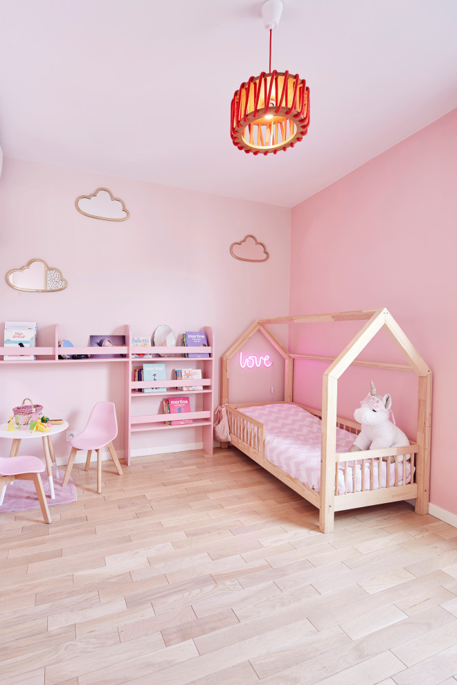 Inspiration for a small contemporary children’s room for girls in Paris with pink walls and light hardwood flooring.
