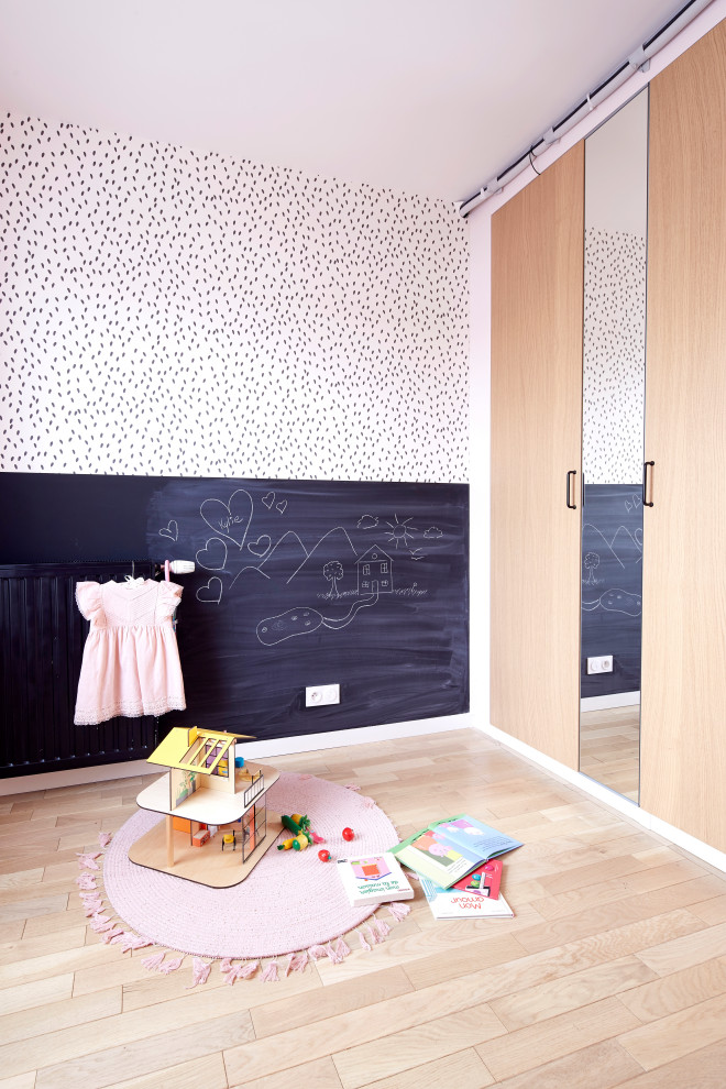 Photo of a small contemporary kids' bedroom for girls in Paris with pink walls and light hardwood flooring.
