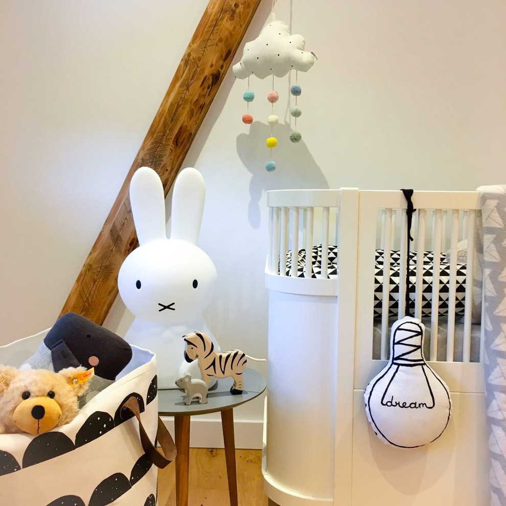 This is an example of a small scandinavian gender neutral toddler’s room in Paris.