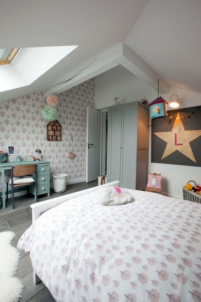 Photo of a large urban children’s room for girls in Lyon with pink walls, light hardwood flooring and brown floors.