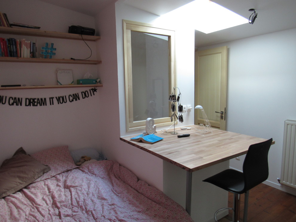 Cette image montre une petite chambre d'enfant minimaliste avec un bureau, un mur rose et parquet clair.
