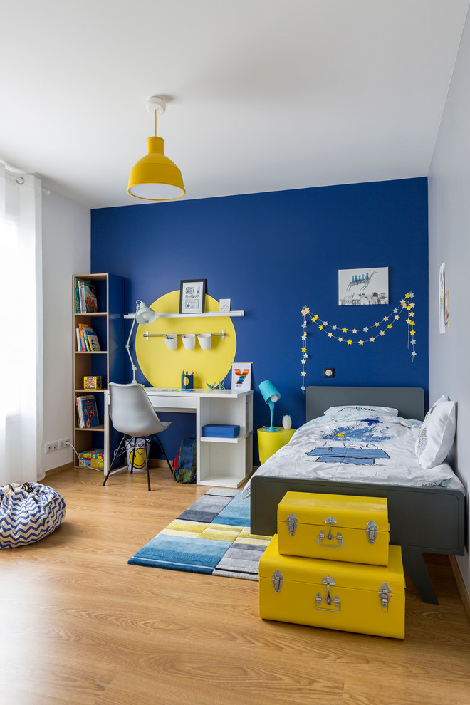 Idée de décoration pour une chambre de garçon de 4 à 10 ans design de taille moyenne avec un mur bleu et parquet clair.