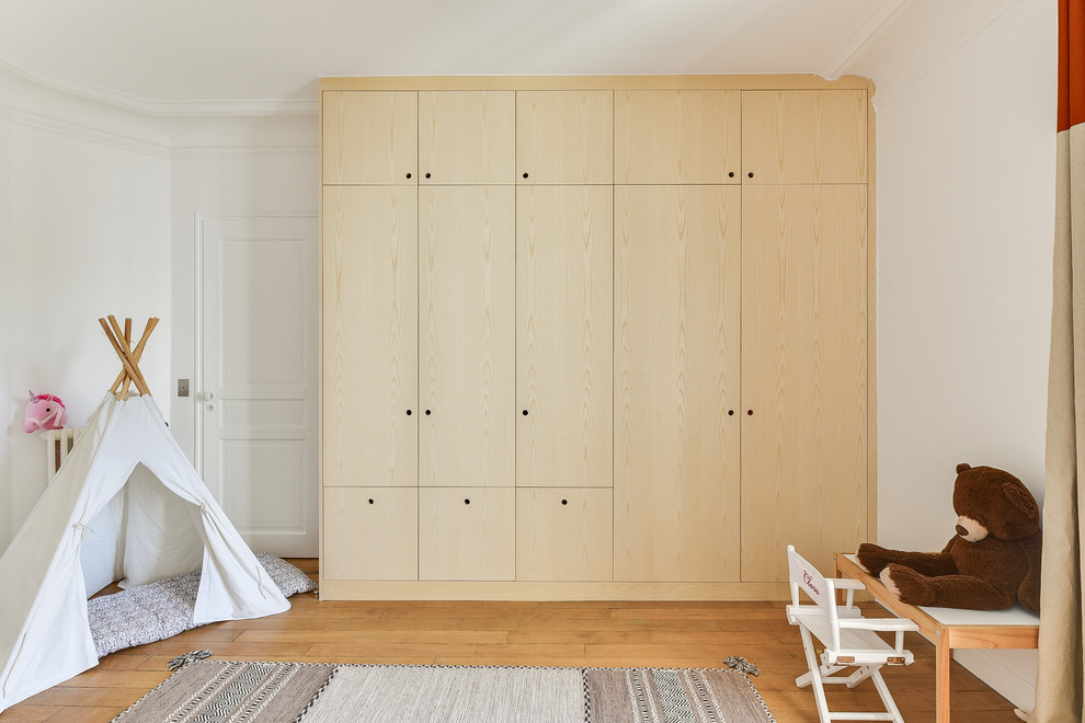 Large contemporary kids' bedroom for girls in Paris with white walls and medium hardwood flooring.