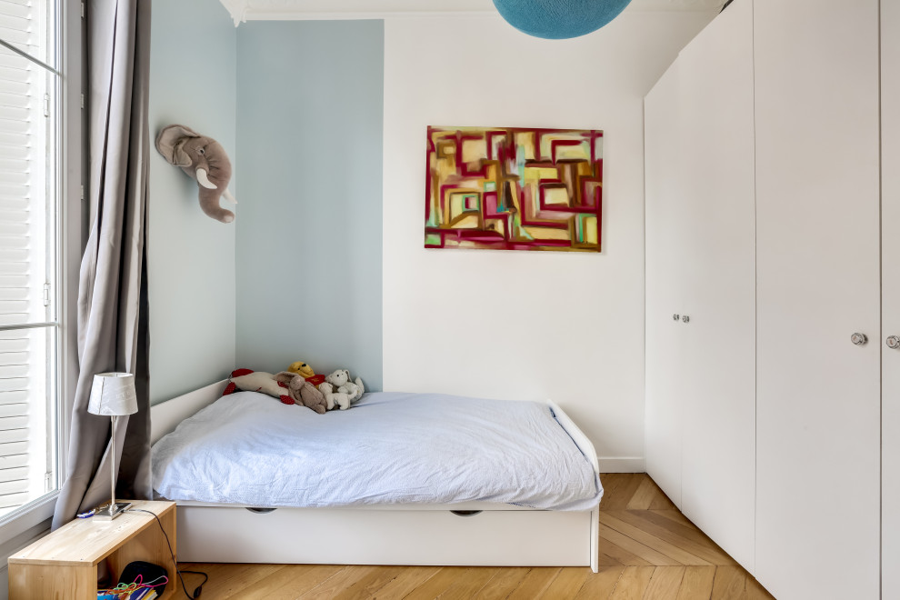 Medium sized contemporary children’s room for boys in Paris with blue walls, brown floors and medium hardwood flooring.