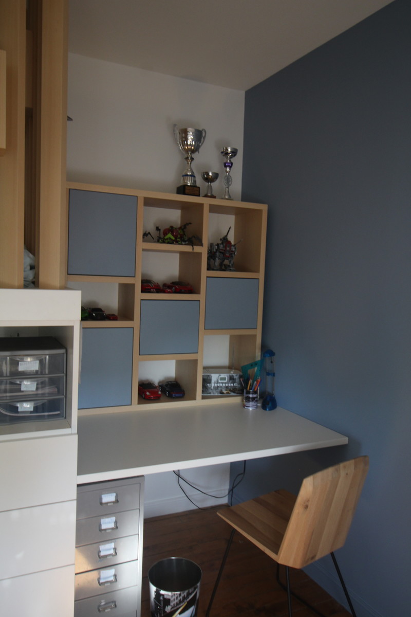 Inredning av ett minimalistiskt mellanstort barnrum kombinerat med skrivbord, med blå väggar, ljust trägolv och brunt golv