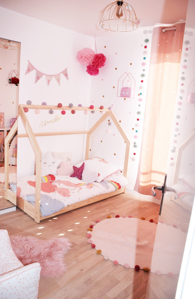 Imagen de dormitorio infantil de 1 a 3 años actual pequeño con paredes rosas, suelo de madera clara y suelo marrón