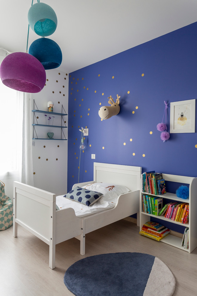 This is an example of a medium sized contemporary toddler’s room for girls in Bordeaux with light hardwood flooring and multi-coloured walls.