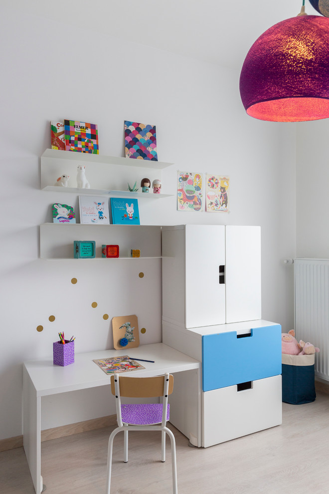 Diseño de habitación de niña de 1 a 3 años actual de tamaño medio con escritorio, paredes blancas y suelo de madera clara