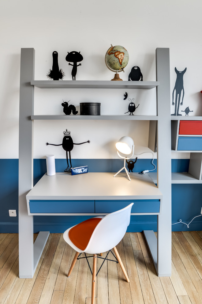 This is an example of a large contemporary gender neutral children’s room in Paris with blue walls and light hardwood flooring.
