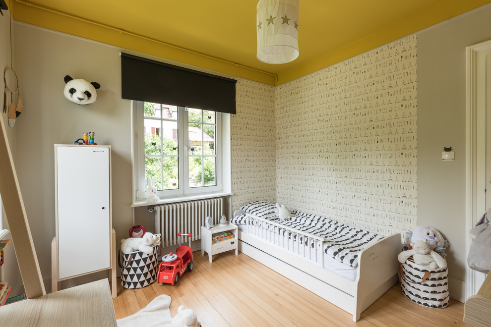 Immagine di una cameretta per bambini da 1 a 3 anni moderna di medie dimensioni con pareti grigie, parquet chiaro e pavimento beige