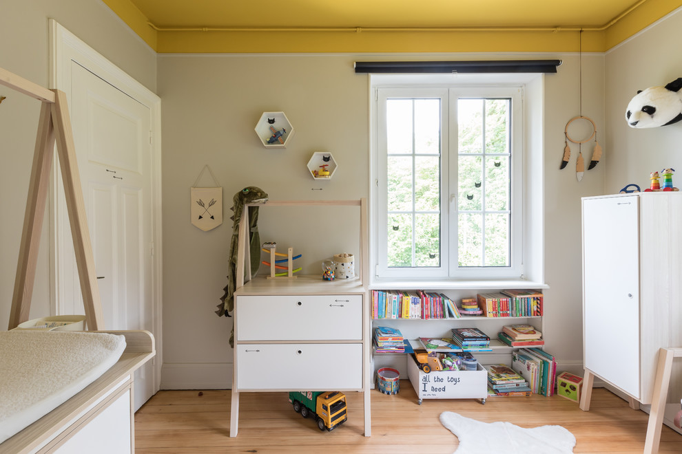 Modelo de dormitorio infantil de 1 a 3 años minimalista de tamaño medio con paredes grises, suelo de madera clara y suelo beige