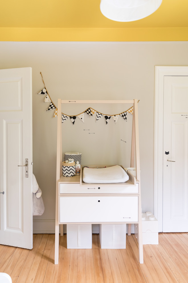 Ejemplo de dormitorio infantil de 1 a 3 años moderno de tamaño medio con paredes grises, suelo de madera clara y suelo beige