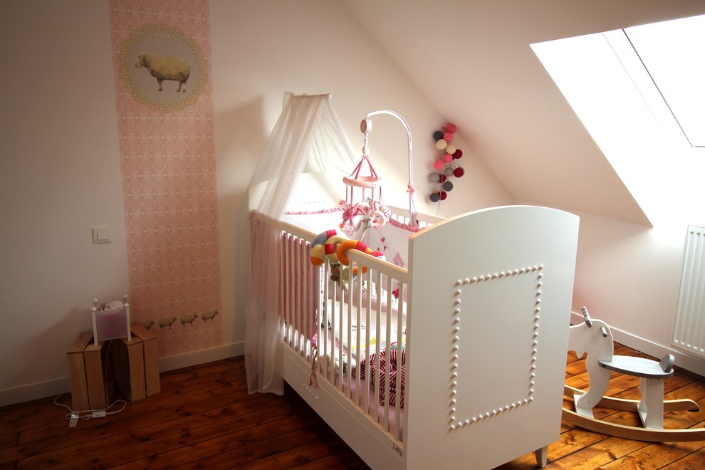 Ispirazione per una cameretta per neonati bohémian con pareti rosa e parquet chiaro