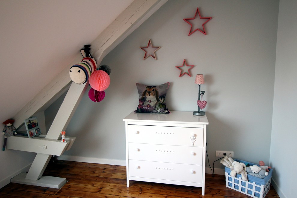 Cette photo montre une chambre d'enfant de 1 à 3 ans éclectique avec un mur gris et parquet clair.