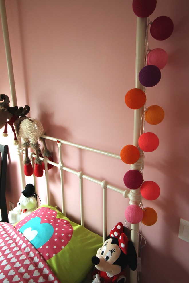 Eklektisk inredning av ett barnrum för 4-10-åringar, med rosa väggar och ljust trägolv