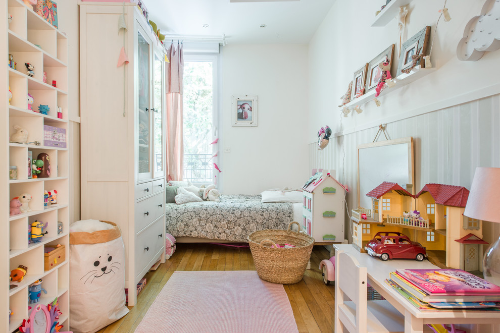 Foto di una cameretta per bambini chic con pareti bianche, pavimento in legno massello medio e pavimento marrone