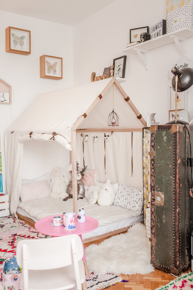 Immagine di una cameretta per bambini bohémian con pareti bianche, parquet chiaro e pavimento marrone