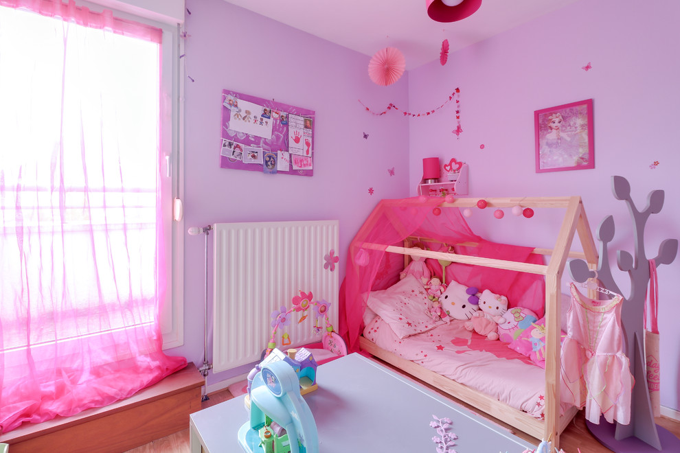 Ispirazione per una cameretta per bambini da 1 a 3 anni tradizionale di medie dimensioni con pareti viola, parquet chiaro e pavimento beige