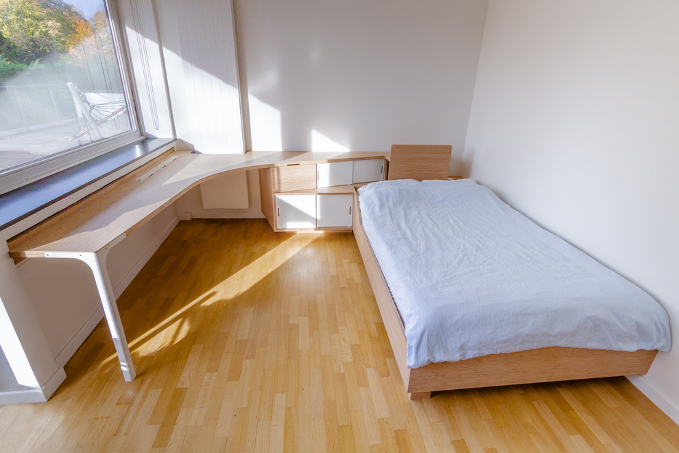 Modern inredning av ett mellanstort barnrum kombinerat med sovrum, med vita väggar, mellanmörkt trägolv och beiget golv