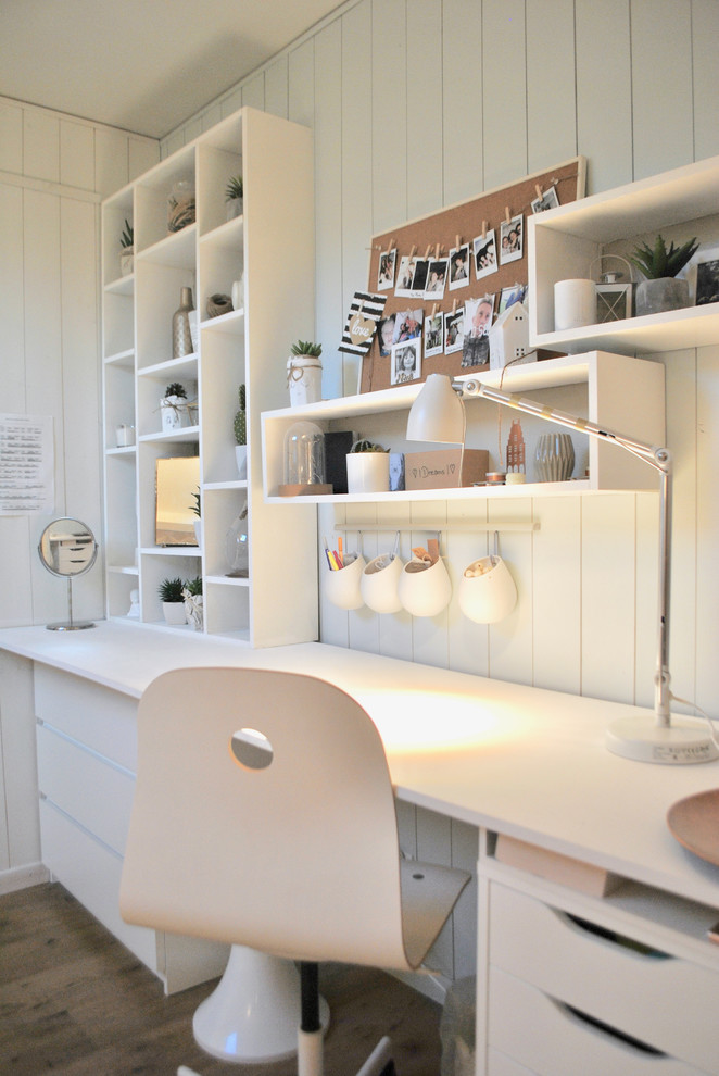 Inredning av ett modernt litet barnrum kombinerat med skrivbord, med vita väggar, ljust trägolv och brunt golv