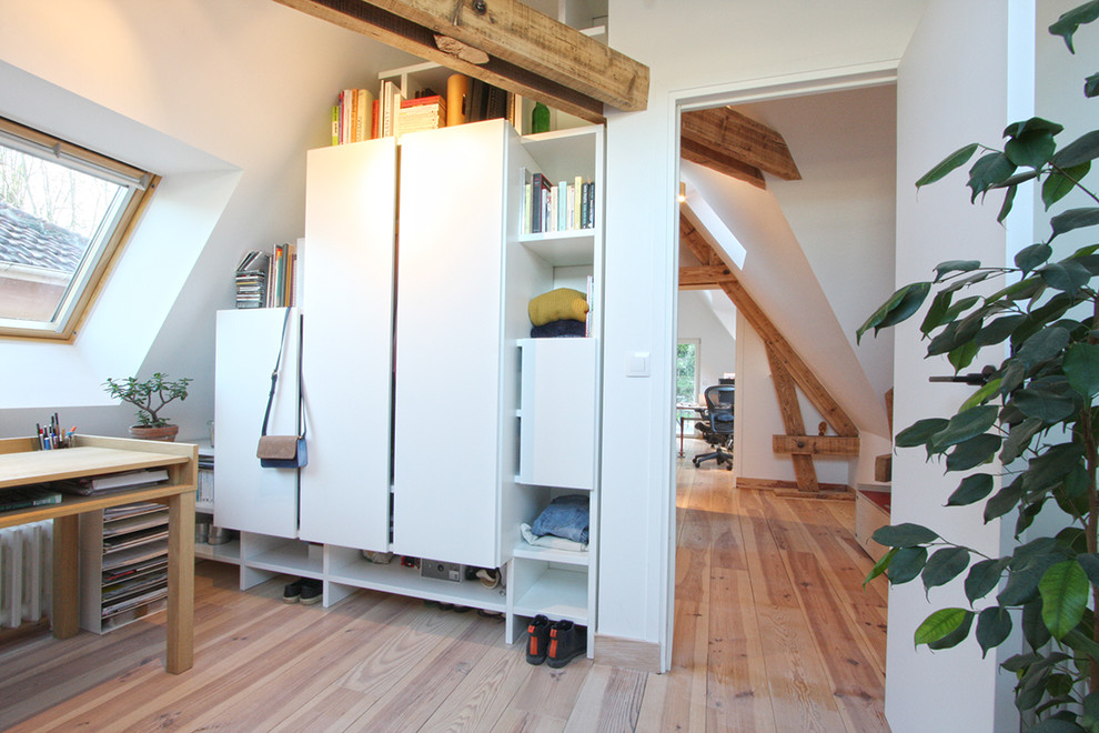 Foto på ett litet funkis könsneutralt tonårsrum kombinerat med sovrum, med vita väggar, ljust trägolv och brunt golv