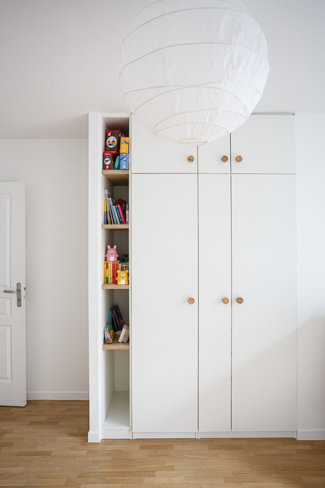 Idee per una cameretta per bambini minimalista di medie dimensioni con pareti bianche, parquet chiaro e pavimento beige
