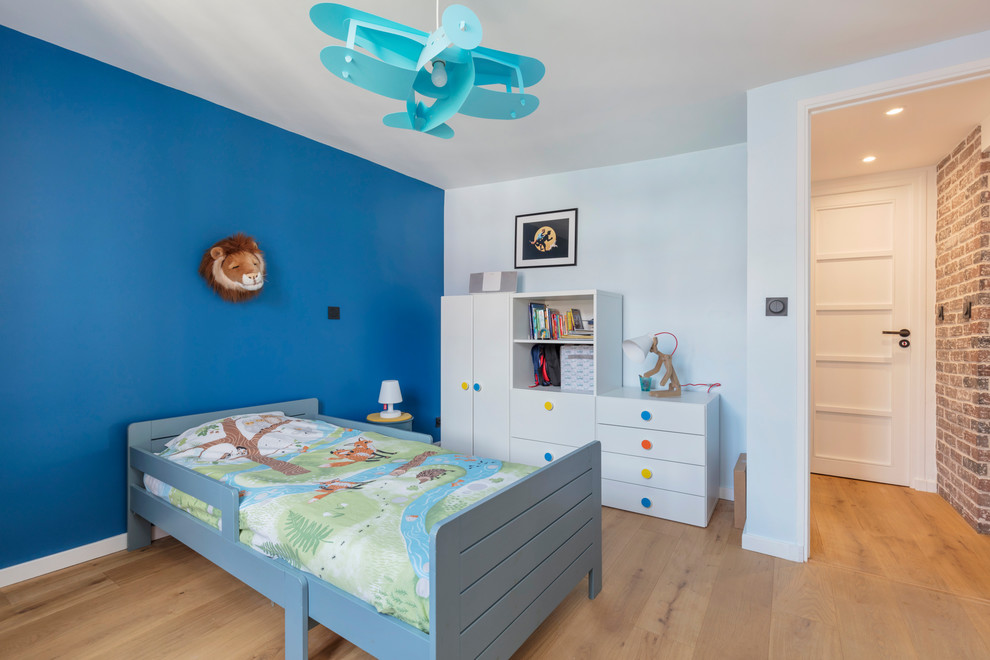 На фото: детская среднего размера в скандинавском стиле с спальным местом, синими стенами и светлым паркетным полом для ребенка от 4 до 10 лет, мальчика с