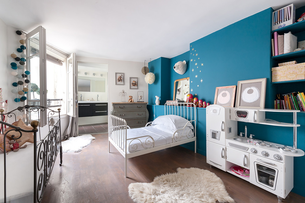 Cette image montre une grande chambre d'enfant de 4 à 10 ans bohème avec un sol en bois brun et un mur multicolore.