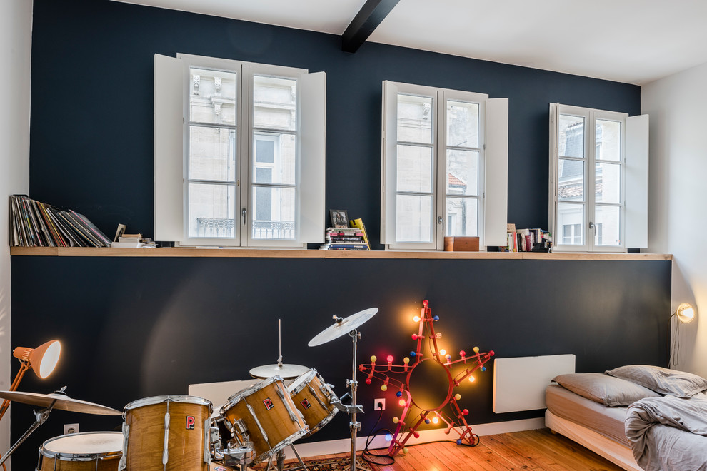 Cette image montre une grande chambre d'enfant minimaliste avec un mur bleu et parquet clair.
