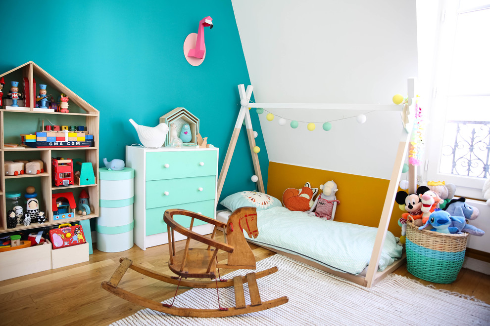 Modelo de dormitorio infantil de 1 a 3 años nórdico con paredes multicolor y suelo de madera en tonos medios