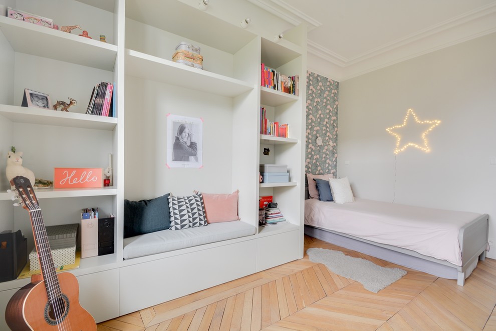 Photo of a medium sized traditional children’s room for girls in Paris with grey walls and light hardwood flooring.