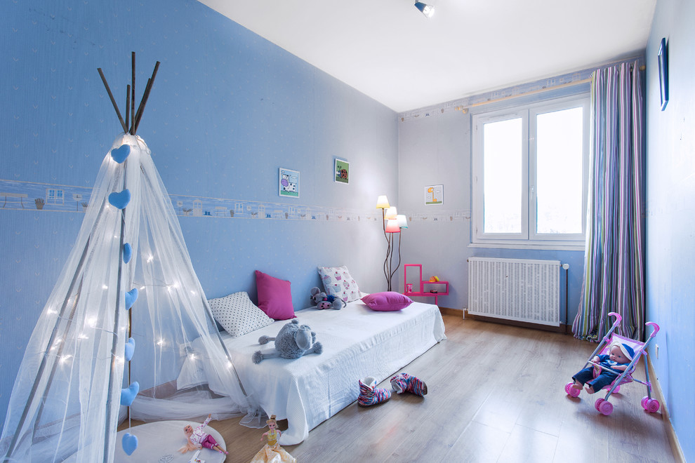 Immagine di una cameretta per bambini da 4 a 10 anni chic di medie dimensioni con pareti blu e pavimento in legno massello medio