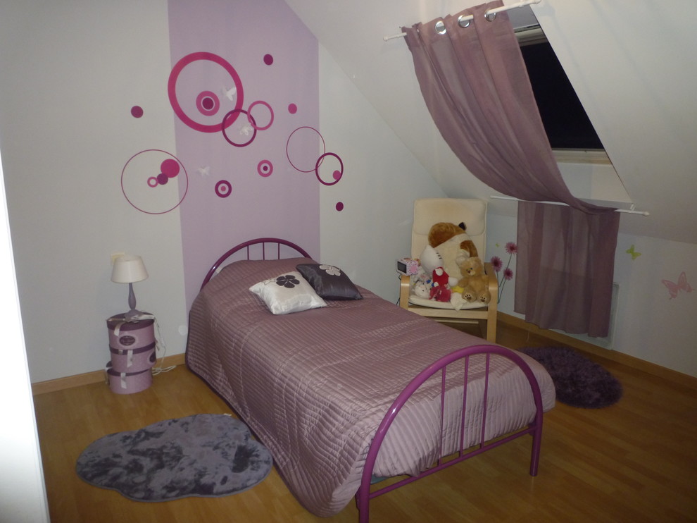 Immagine di una grande cameretta per bambini da 4 a 10 anni minimalista con pareti viola, pavimento in laminato e pavimento beige