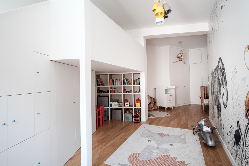 Idéer för funkis könsneutrala barnrum kombinerat med lekrum, med vita väggar, mellanmörkt trägolv och brunt golv