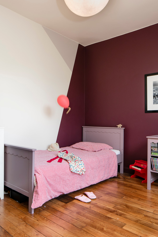 This is an example of a medium sized contemporary children’s room for girls in Paris with white walls and light hardwood flooring.