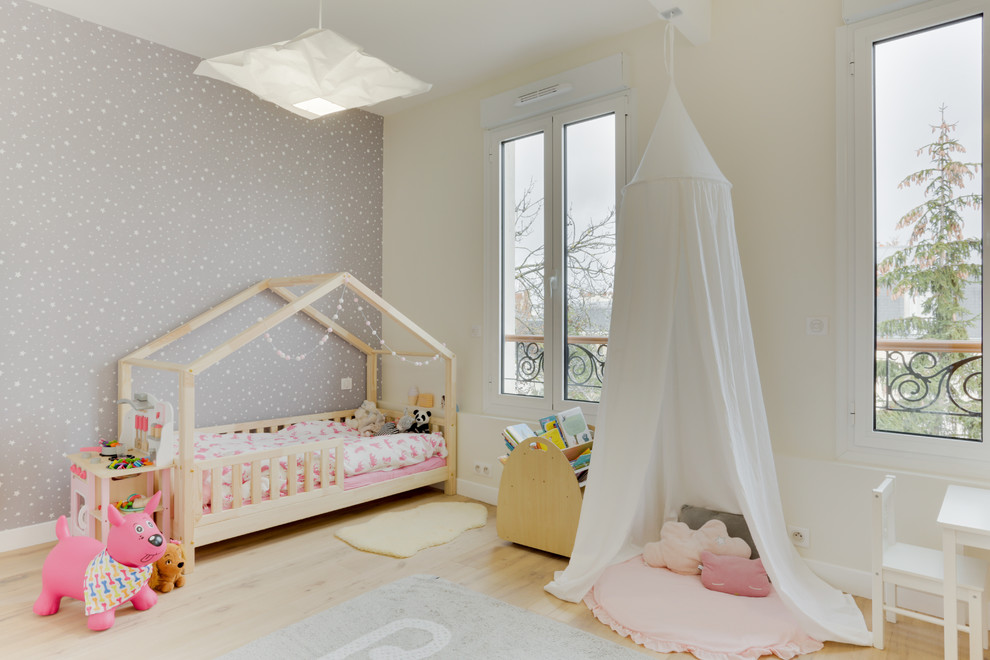Photo of a large scandi toddler’s room for girls in Paris with grey walls, light hardwood flooring and beige floors.