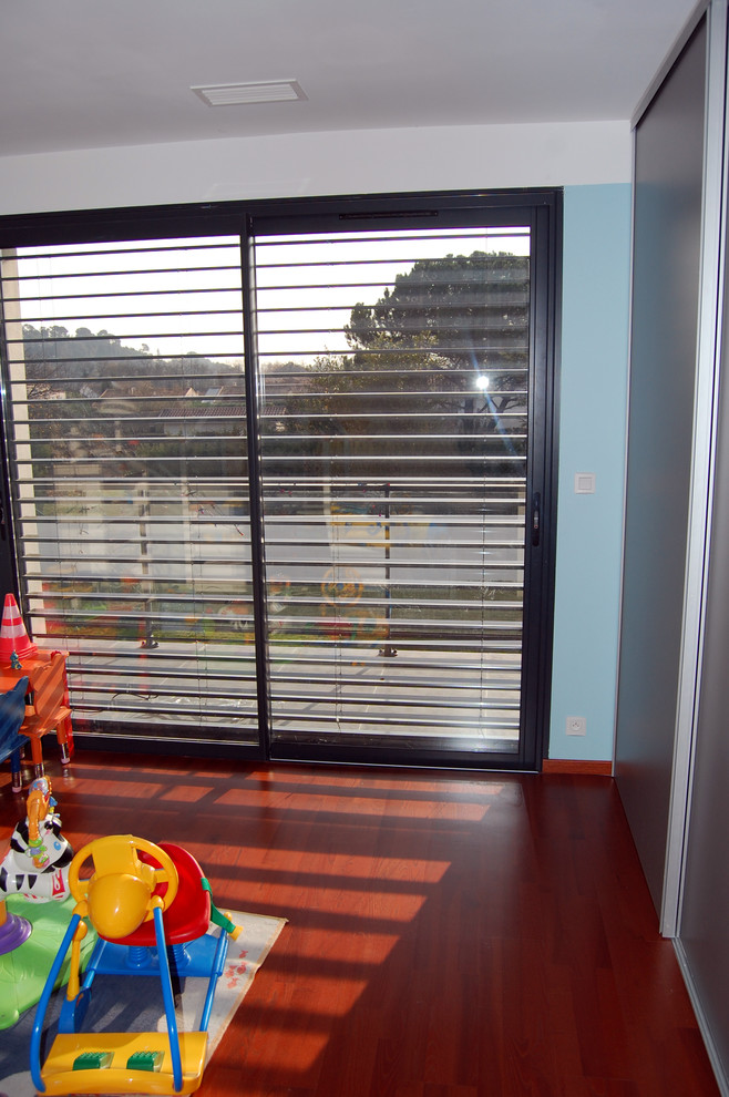 Cette image montre une grande chambre d'enfant de 1 à 3 ans design avec parquet foncé et un mur multicolore.