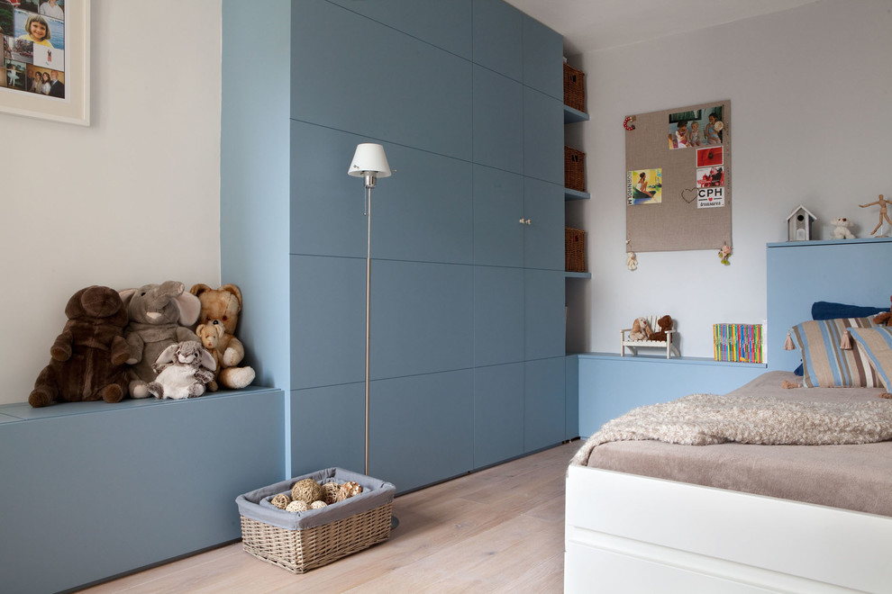 Imagen de habitación infantil unisex de 4 a 10 años actual de tamaño medio con paredes blancas, suelo de madera clara y suelo marrón