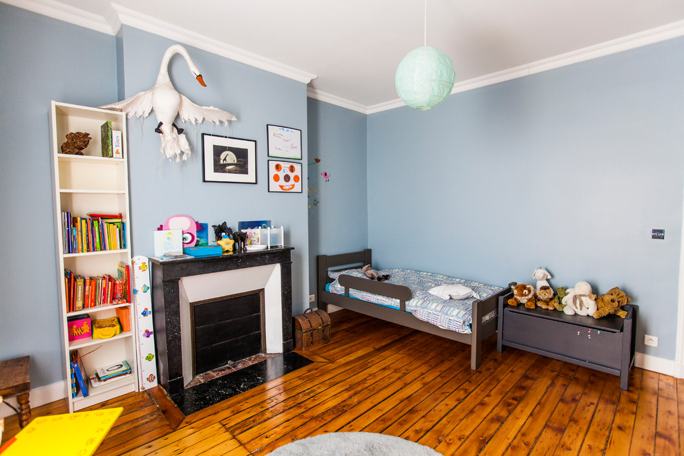 Exemple d'une chambre d'enfant de 4 à 10 ans tendance de taille moyenne avec un mur bleu et un sol en bois brun.