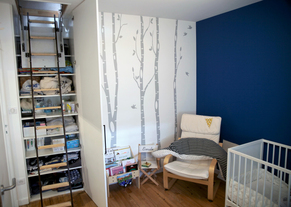 Immagine di una cameretta per bambini da 1 a 3 anni contemporanea di medie dimensioni con pareti blu, parquet chiaro e pavimento marrone