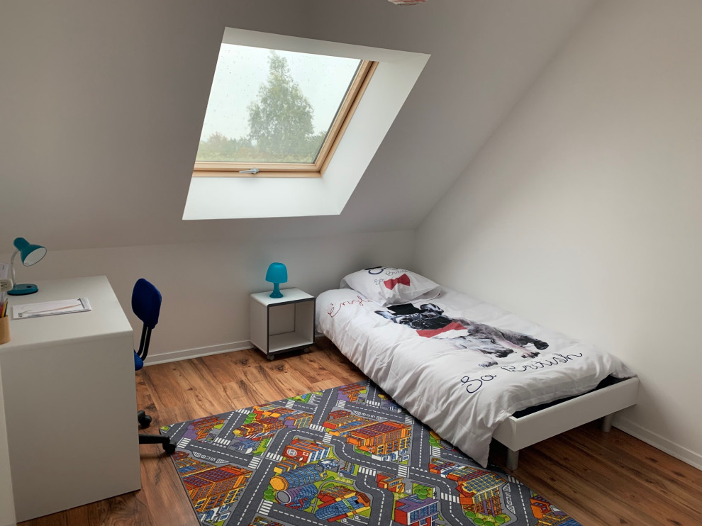 Klassisk inredning av ett mellanstort könsneutralt barnrum kombinerat med sovrum och för 4-10-åringar, med vita väggar, laminatgolv och brunt golv