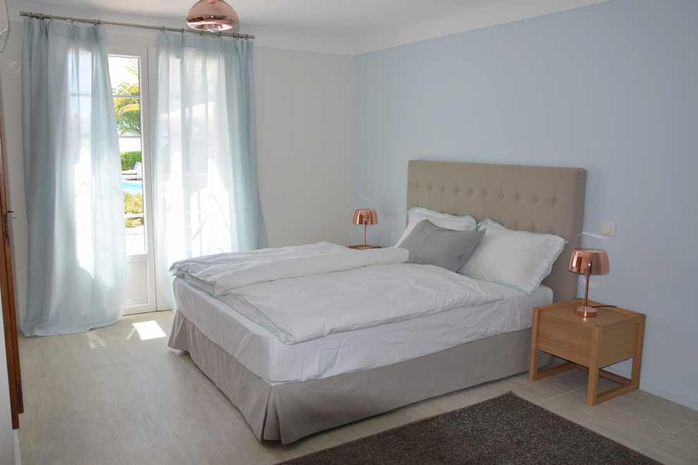 На фото: спальня среднего размера в стиле кантри с синими стенами, полом из травертина и бежевым полом