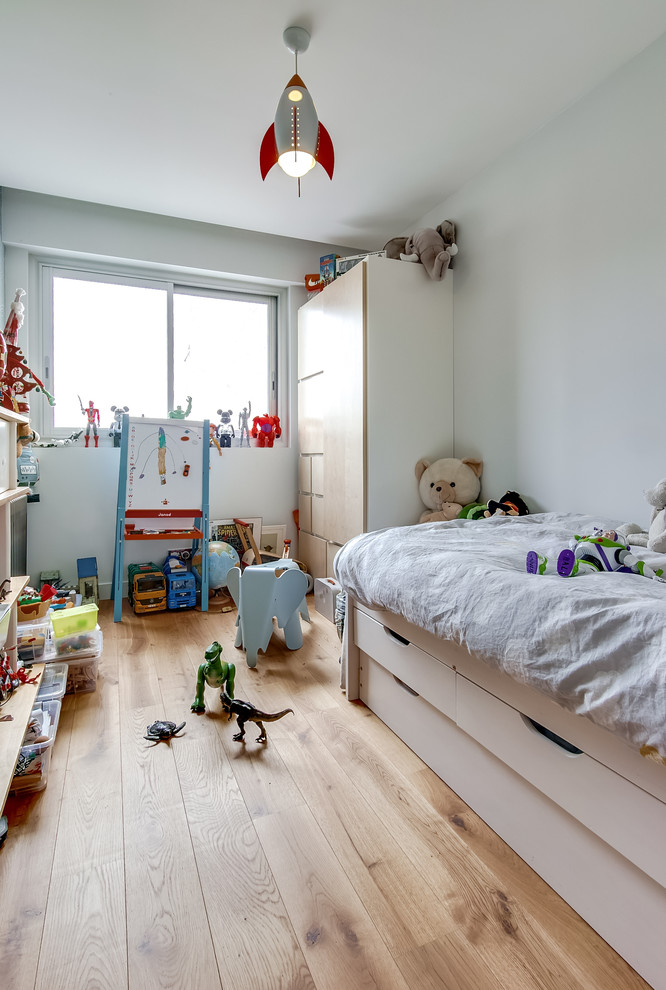 Modelo de dormitorio infantil de 4 a 10 años contemporáneo pequeño con paredes blancas y suelo de madera clara