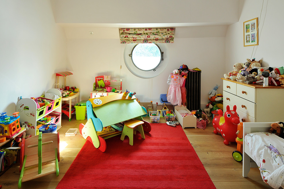 Modern inredning av ett mellanstort barnrum kombinerat med sovrum, med vita väggar, ljust trägolv och beiget golv
