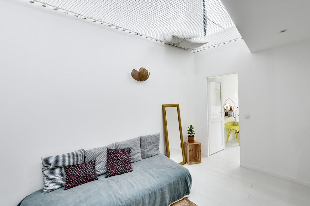 Mid-sized trendy gender-neutral painted wood floor playroom photo in Paris with white walls
