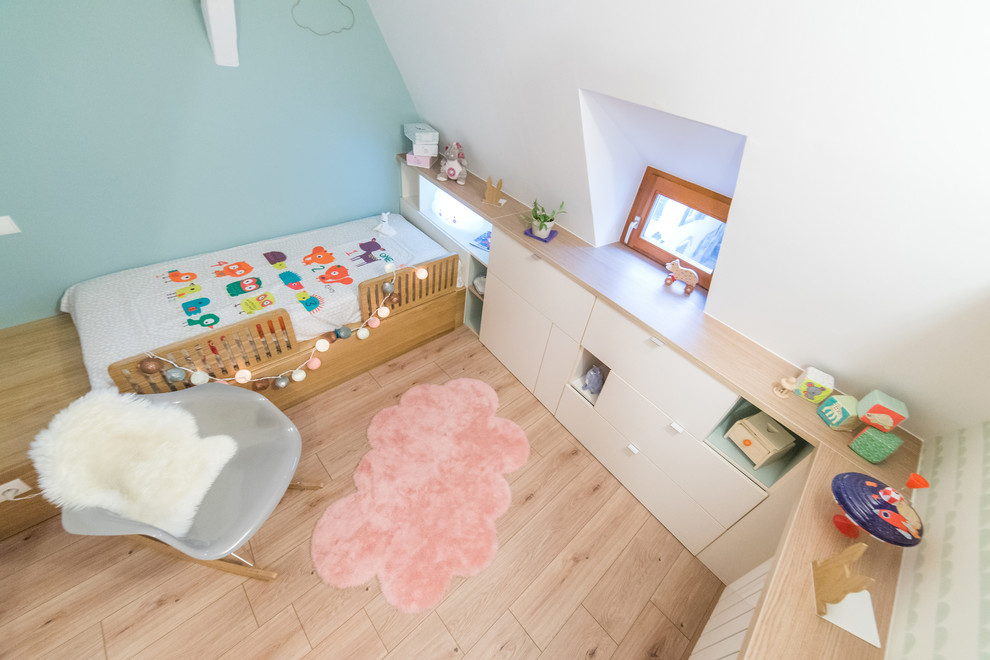 Immagine di una piccola cameretta per bambini da 1 a 3 anni scandinava con parquet chiaro, pavimento beige e pareti bianche